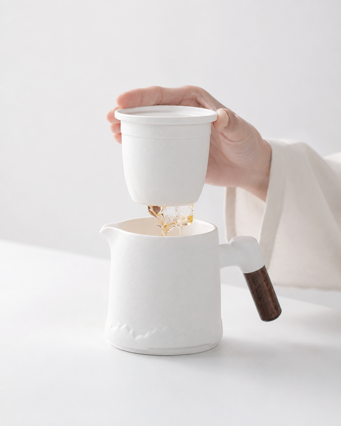 A removable ceramic infuser lifted from a handled travel tea pot