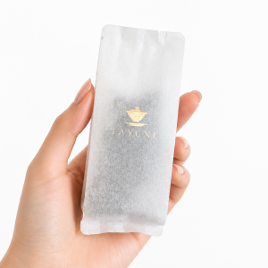 Hand holding one 10 g TAYUNE Pu-erh tea sample sachet