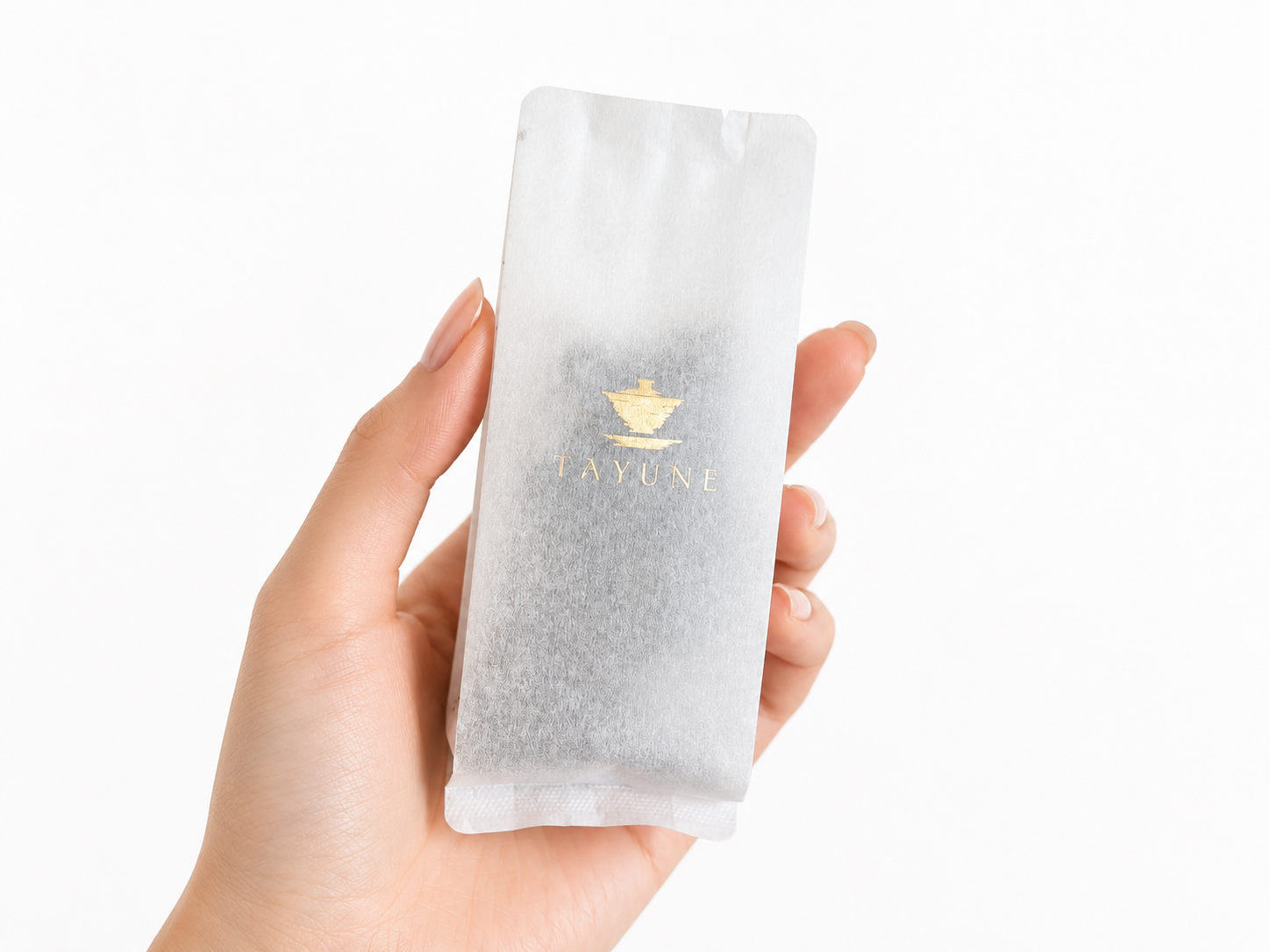 Hand holding one 10 g TAYUNE Pu-erh tea sample sachet